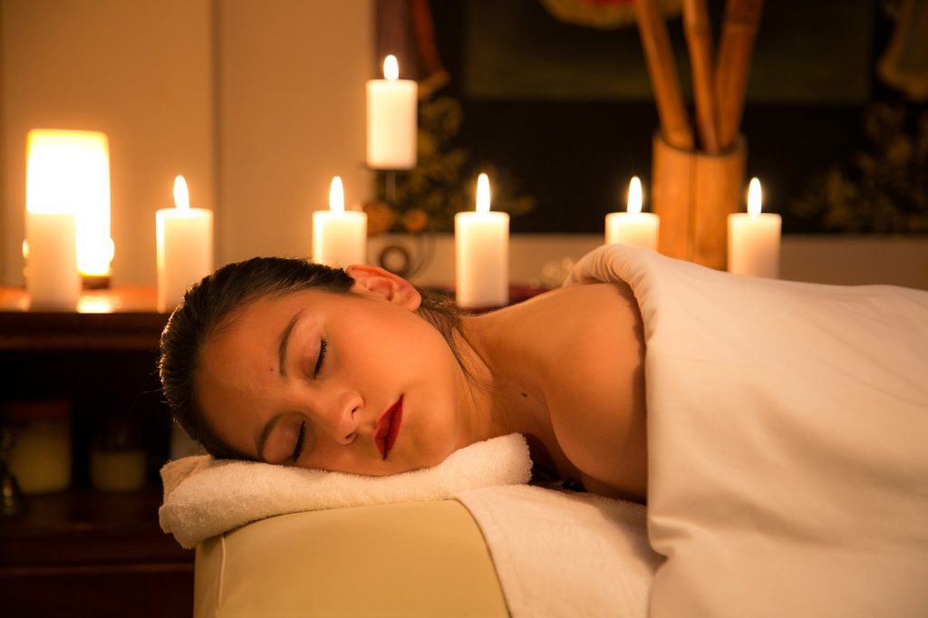 Mulher relaxando a luz de velas após uma massagem terapêutica 