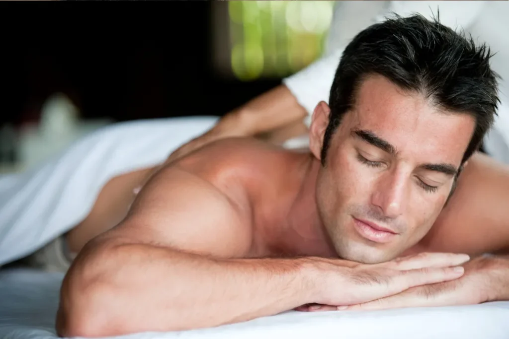 Homem relaxando durante uma sessão de massagem, deitado de bruços com expressão tranquila