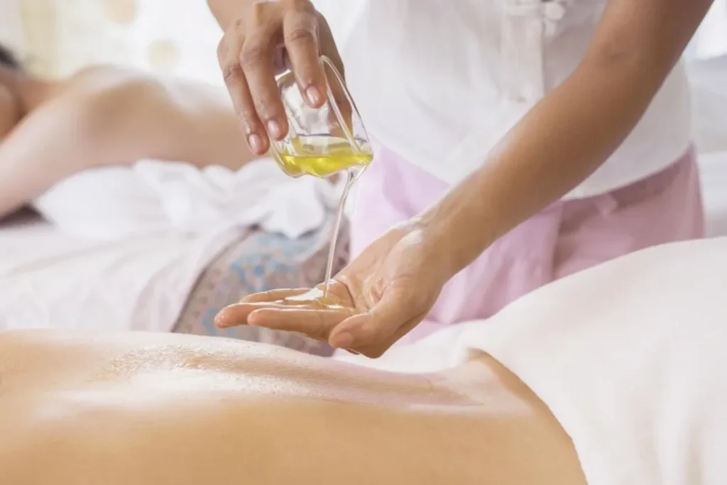 Terapeuta aplicando gel lubrificante nas mãos antes de massagear as costas de um paciente.