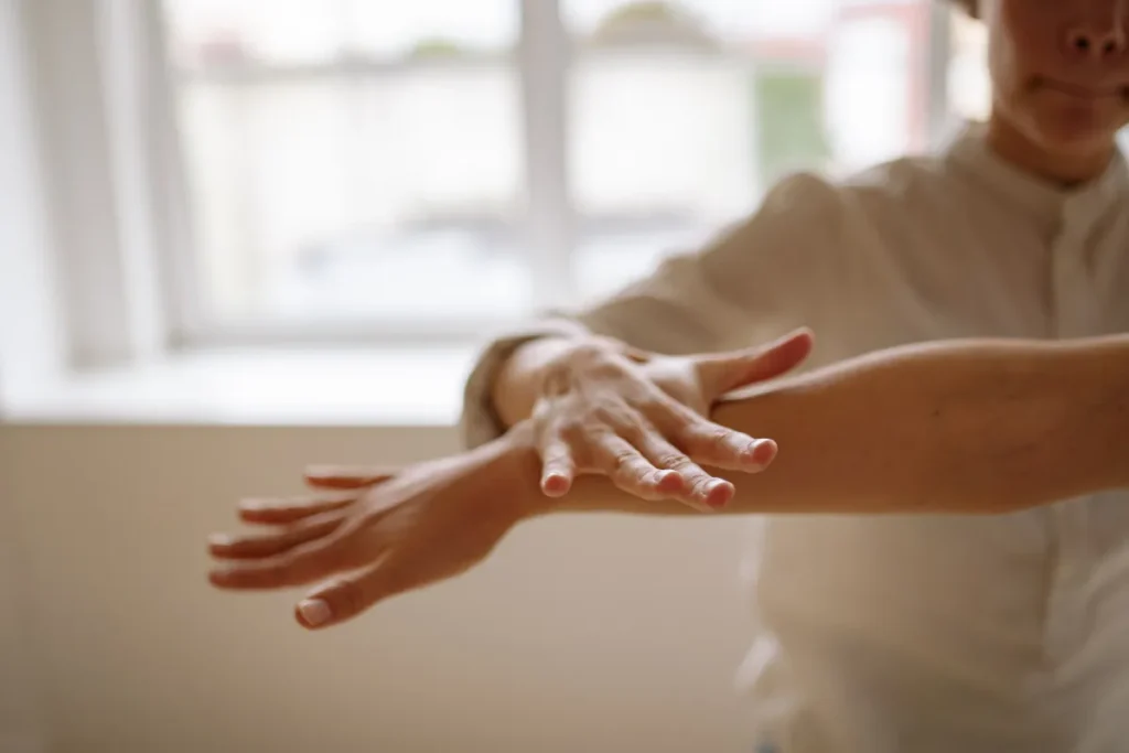 Pessoa pressionando e massageando o próprio braço com a mão para aliviar desconforto muscular