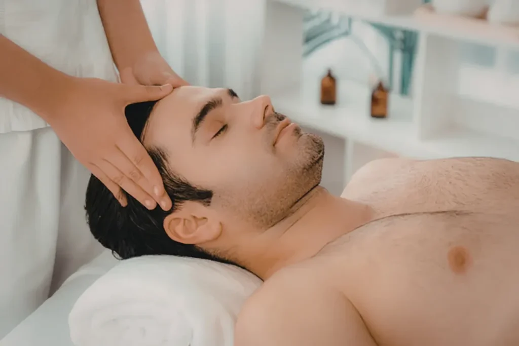 Homem deitado recebendo massagem na cabeça com mãos do terapeuta