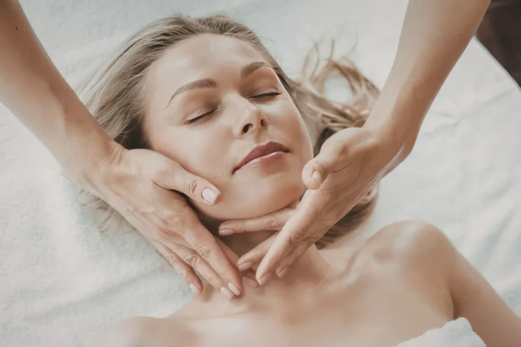 Mulher deitada recebendo massagem facial com as mãos do terapeuta