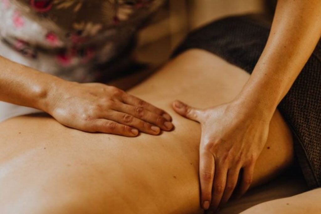 Close de mãos de um terapeuta aplicando massagem suave nas costas de uma pessoa.